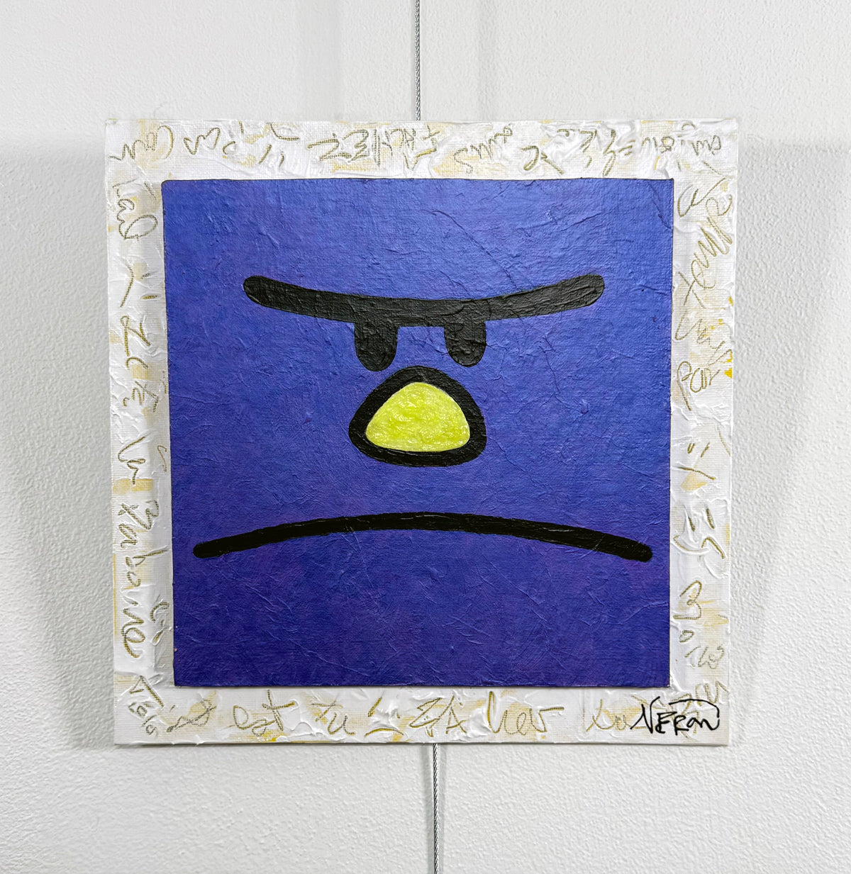 Pop-art square painting of a purple character with a frowning expression, yellow nose, and bold black features, framed by a white border with gold scribbles. Mixed-media artwork by Audrey Néron.