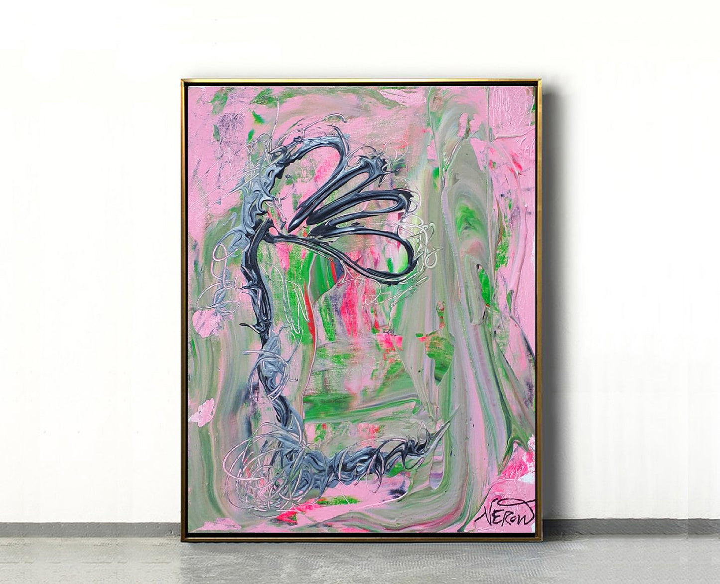 Framed view of the abstract painting Louna (2019) by Audrey Néron, featuring a stylized floral black and grey form over a fluid pink and green background. The artwork is displayed against a white wall on a grey floor, set in a thin gold frame.